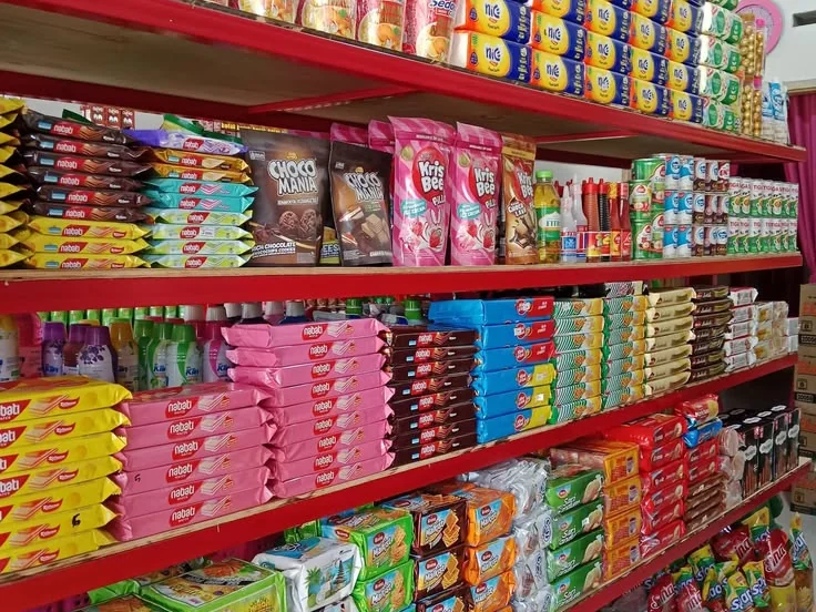 Red supermarket shelves neatly stocked with biscuits, wafers, snacks and drinks