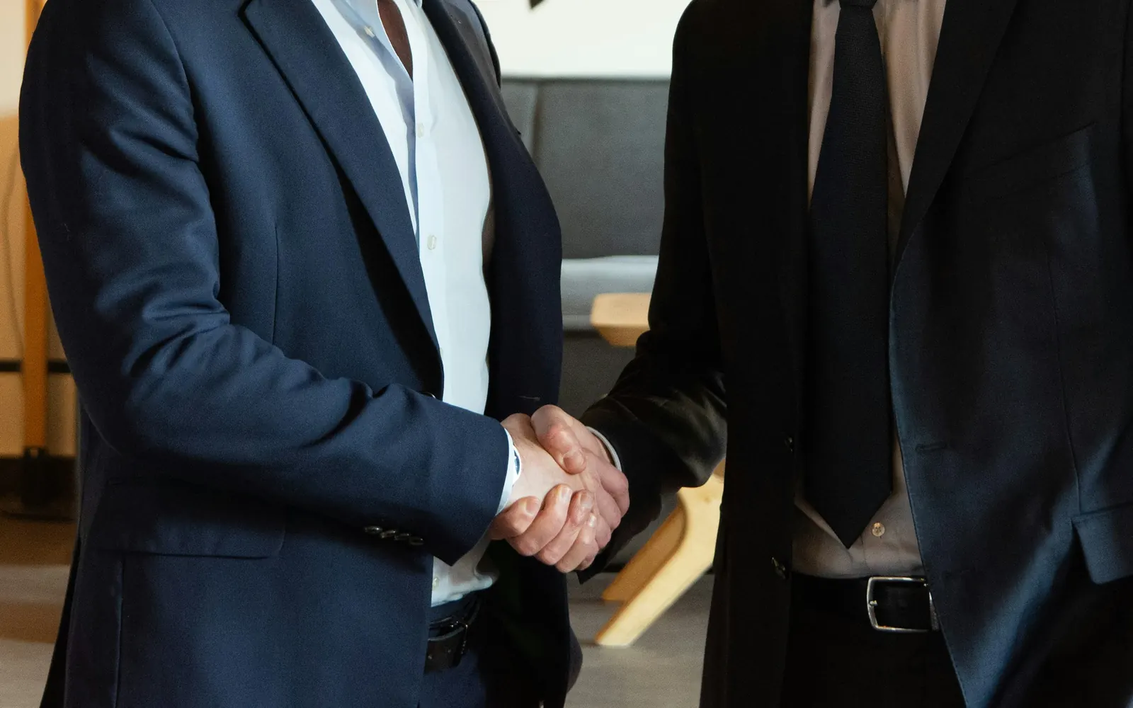 Two business partners in suits shaking hands after agreeing an investment partnership