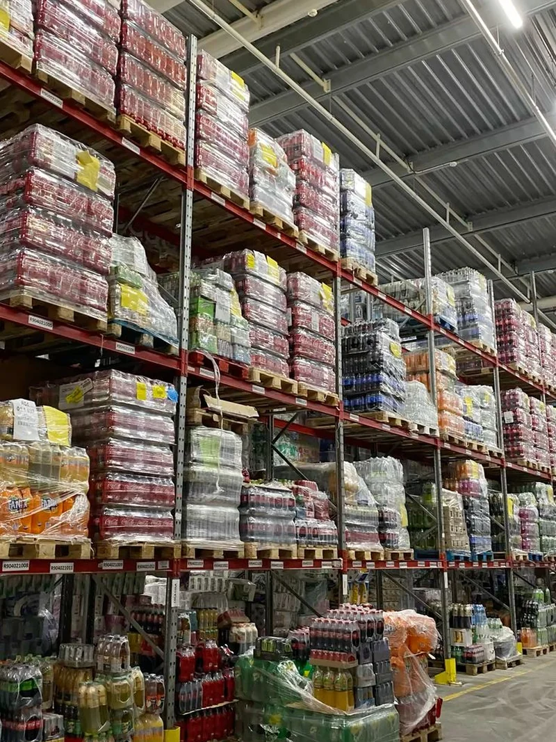Warehouse racks stacked with pallets of packaged drinks and grocery stock